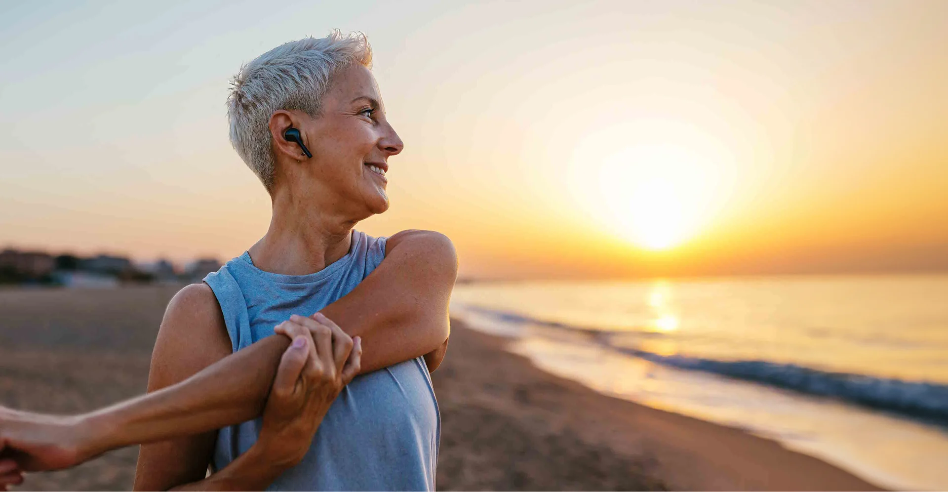 woman doing stretches on the beach at sunset