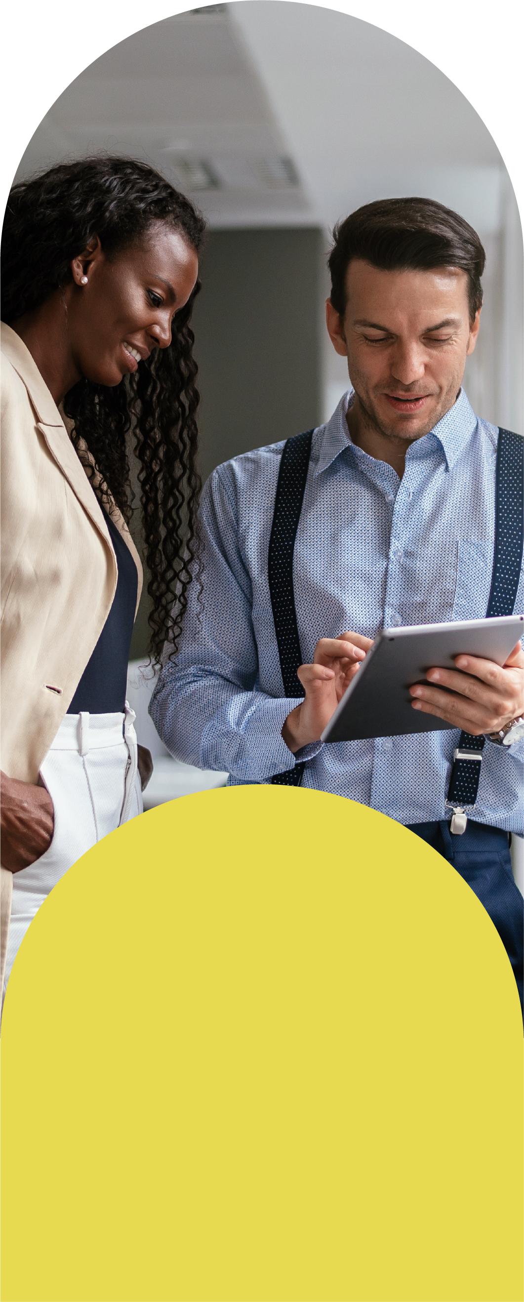 Two people discussing something while one holds a tablet and the other has hands in pockets.